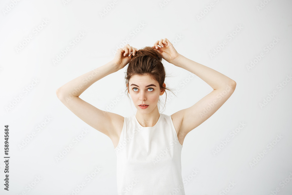 Young beautiful girl correcting hair bun over white background. Young beautiful girl correcting hair bun over white background.