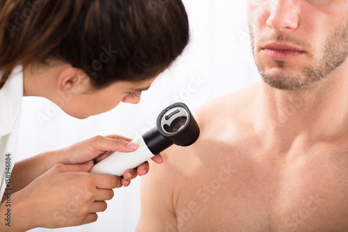 Doctor Examining Man's Shoulder With Dermatoscope