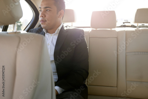 Pensive young man in the back seat of a car