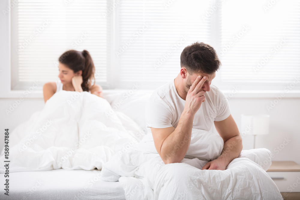 Worried Couple Sitting On Bed Worried Couple Sitting On Bed
