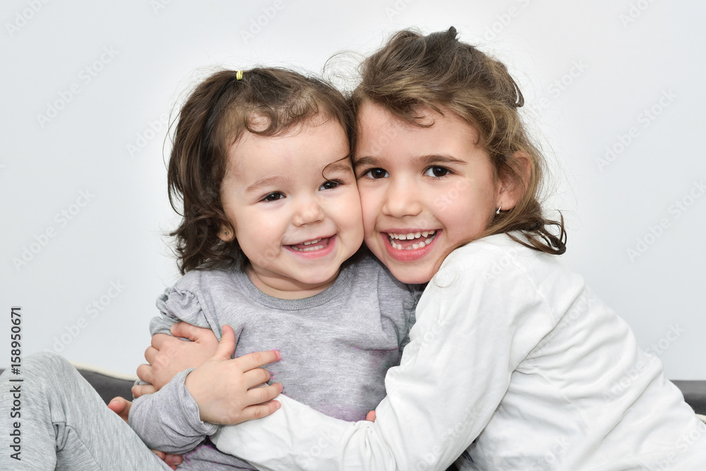 Hugging and smiling sisters cheek to cheek