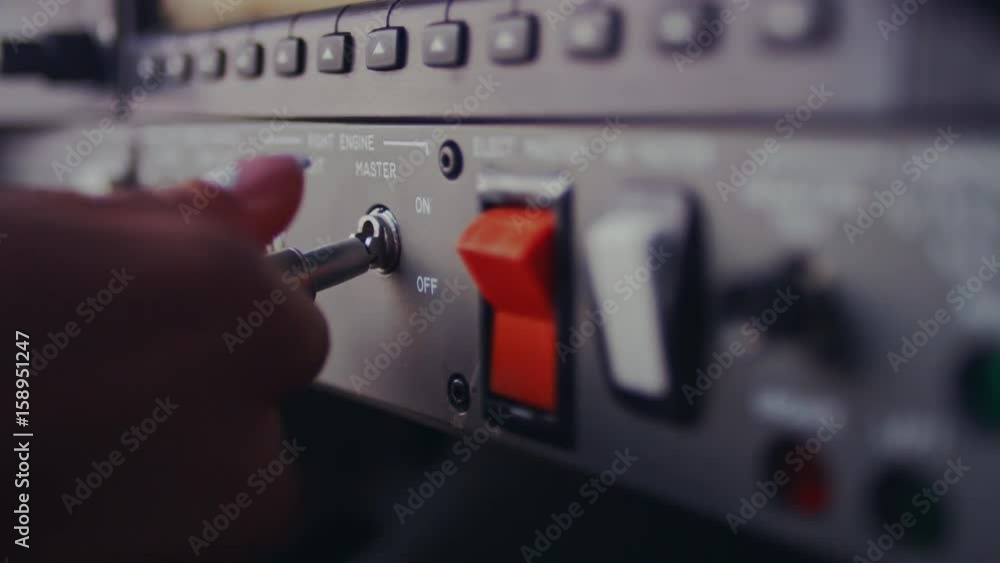 Female hand switch toggle on airplane control panel. Control buttons on plane panel. Close up of female hand switch tumbler on dashboard. Instrumental control panel of aircraft cockpit
