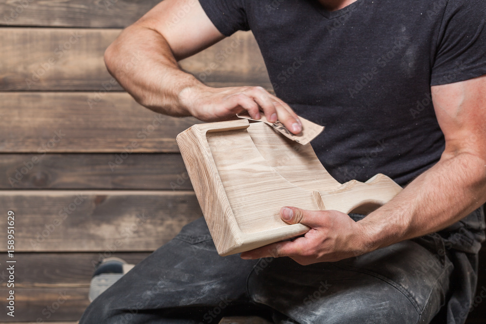 Close-up of a young male carpenter leveling a wooden product in a workshop Close-up of a young male carpenter leveling a wooden product in a workshop