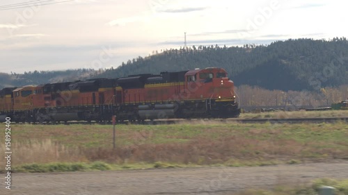 BILLINGS, MONTANA, CLOSE UP: Locomotive hauling freight train wagons loaded with coal along the hilly landscape across America. Train moving on railroad tracks transporting goods photo