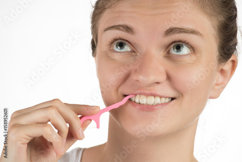 Hygiene of the oral cavity. Young girl cleans teeth with floss  smiling and showing okay sign on a background.