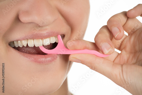 Hygiene of the oral cavity. Young girl cleans teeth with floss, smiling and showing okay sign on a background.