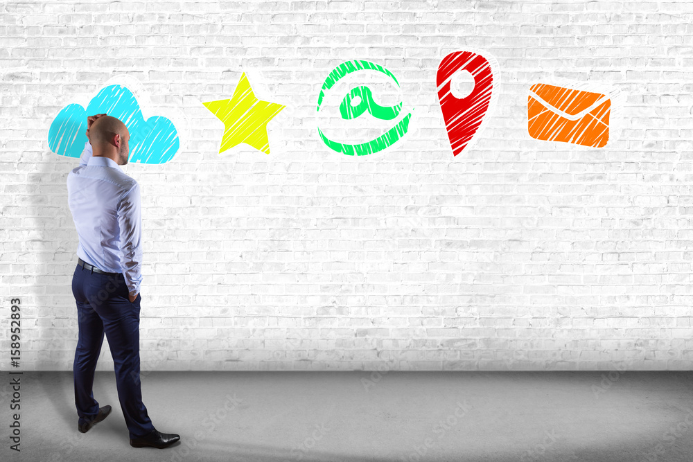 Businessman in front of a wall thinking about application multimedia internet - Internet concept