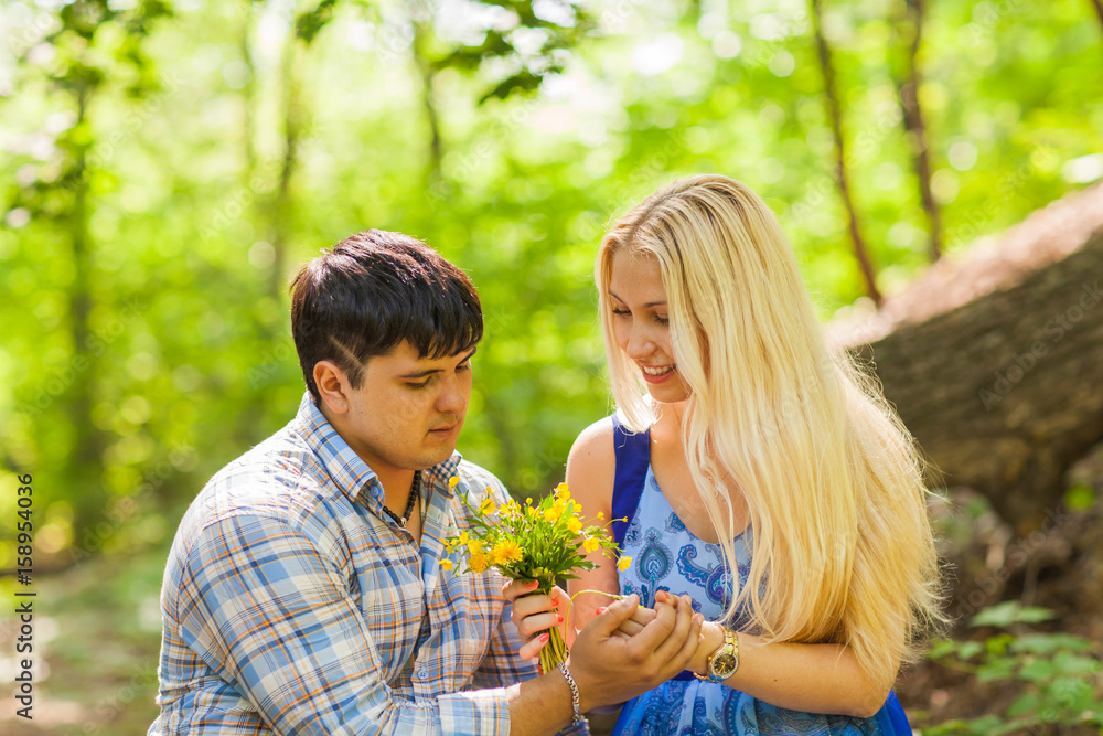 Fototapeta premium Young man giving a flower dandelion to girlfriend outdoors