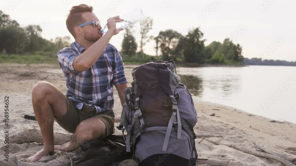 Young Man Sitting and Drinking Water From the Bottle