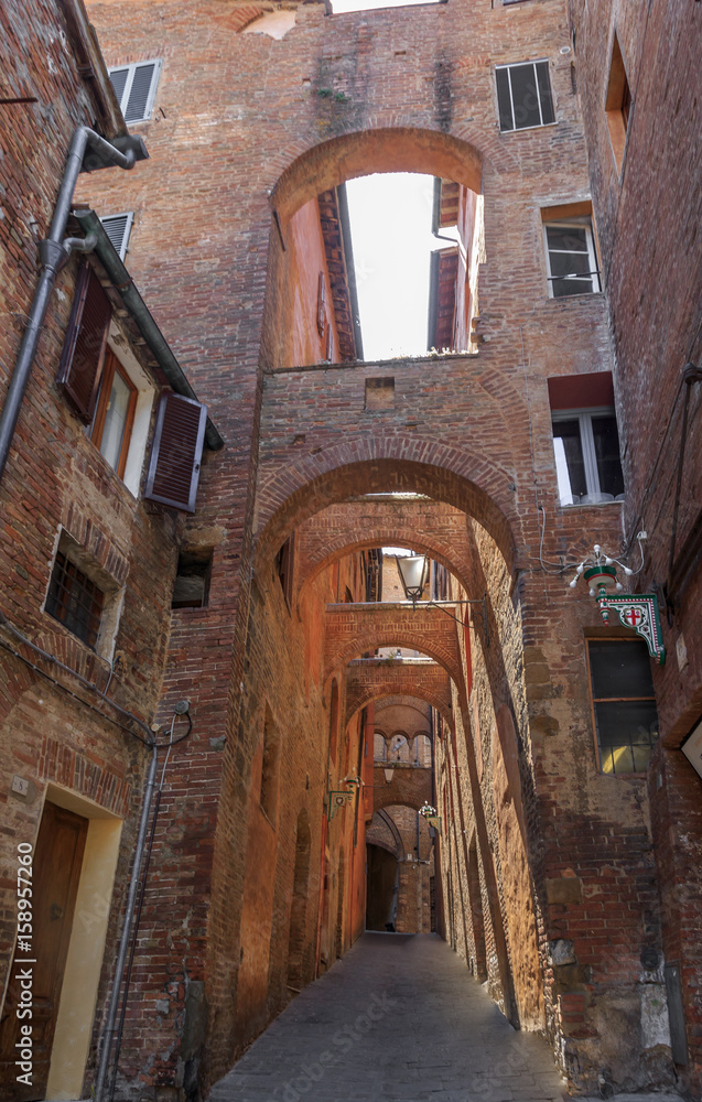 Narrow streets built of red bricks in medieval Siena. Characteristic is  large number of struts between buildings