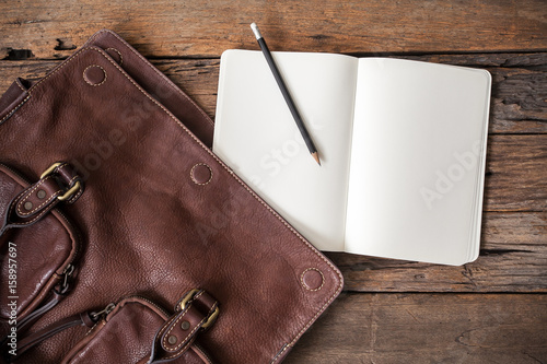 blank notebook with leather bag on wooden table