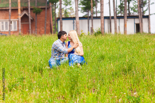 Happy young couple relaxing on the lawn in a summer park. Love concept. Vacation. © satura_