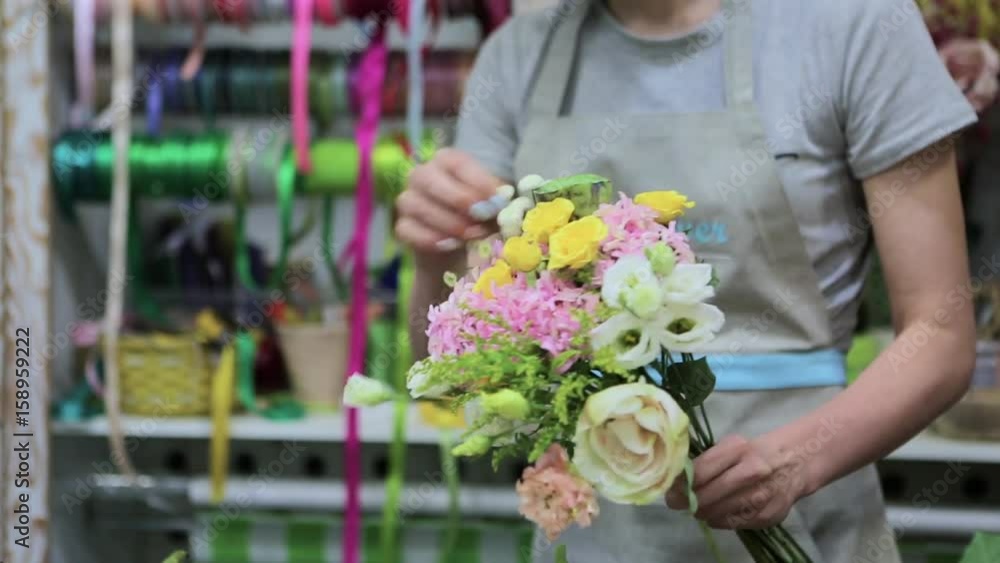 Female florist Arranging Flowers In Flower Shop