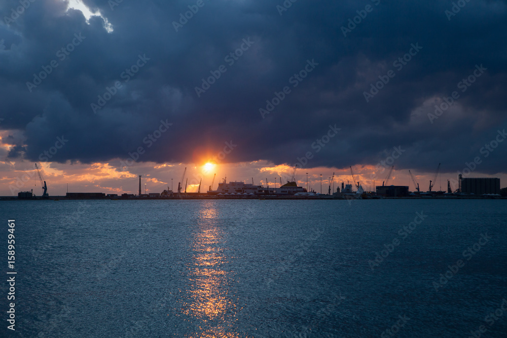 Sunrise over the sea with threatening clouds in the background of the commercial port