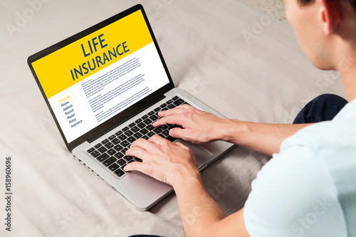 Life Insurance concept: Man typing in a laptop computer with Life Insurance contract in the screen.