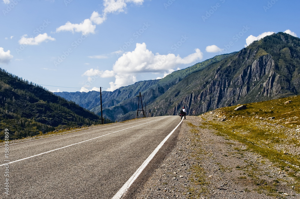 Fototapeta premium Chuiski road, Altai Republic. The road in the mountains, highway, paved road near the shore of the river Chuya. Sunny day in summer. Biking, cycling, cyclist.