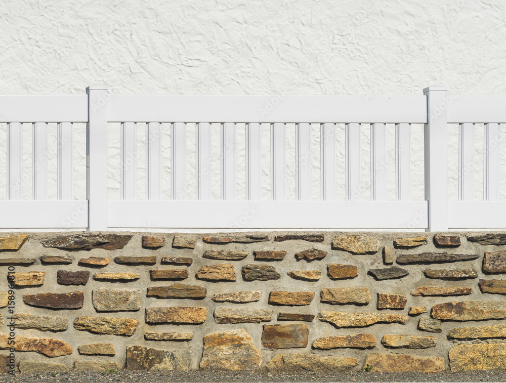 Gartenzaun aus Kunststoff in Weiß aus PVC auf einer Natursteinmauer