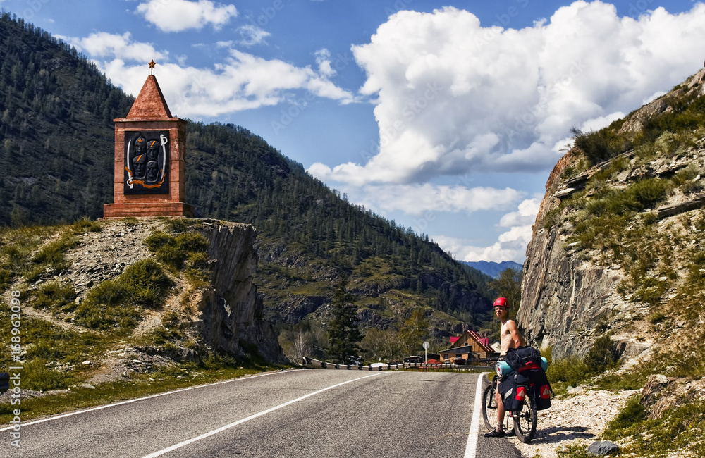 Fototapeta premium Chuiski road, Altai Republic. The road in the mountains, highway, paved road near the shore of the river Chuya. Sunny day in summer. Biking, cycling, cyclist.