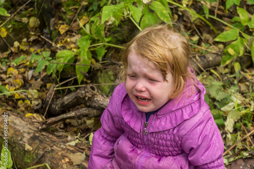 little girl very much crying in the woods outdoors, she was lost in the woods, lost, or get hurt, the girl wants to mother.
