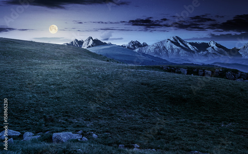 meadow with huge stones on top of mountain range at night