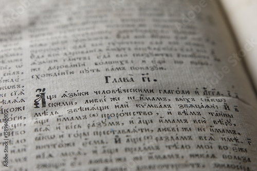 Open book with light spotlight on text. Reading of opened book educate reader. Ancient Bible text reading on black background. Russian bible