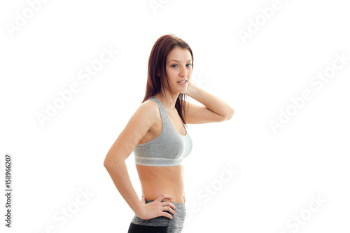 smiling young brunette in athletic top keeps his hand on the side and looks away