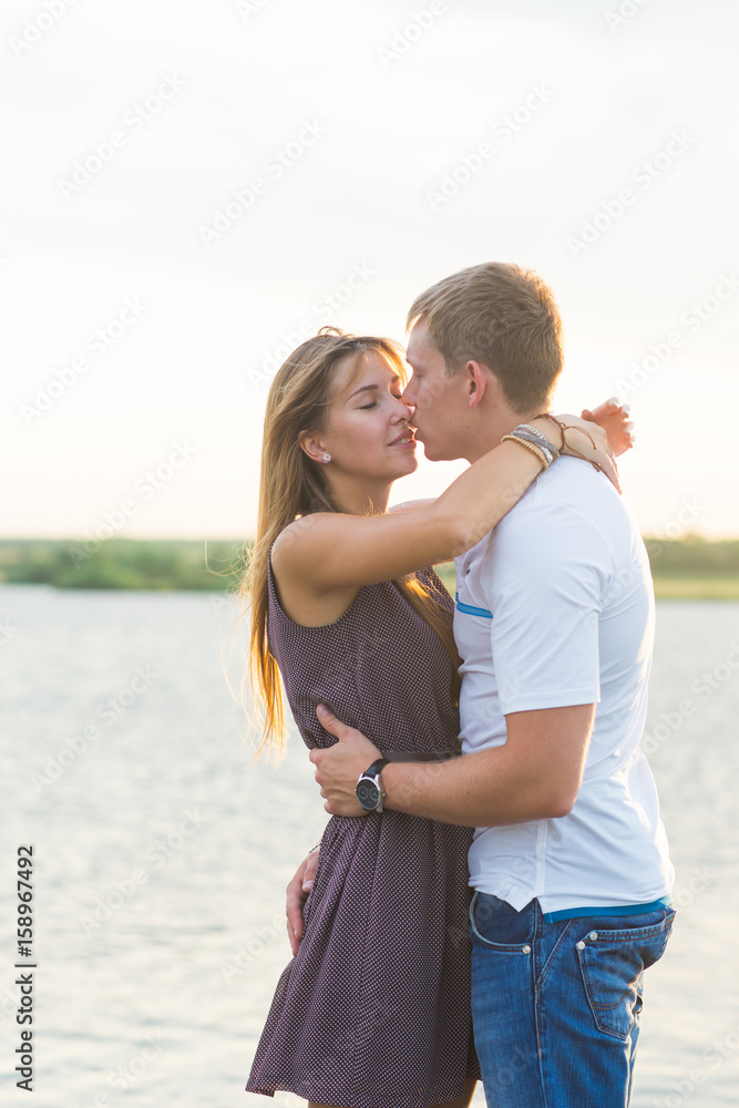 Young couple in love outdoors embracing together at lake Young couple in love outdoors embracing together at lake