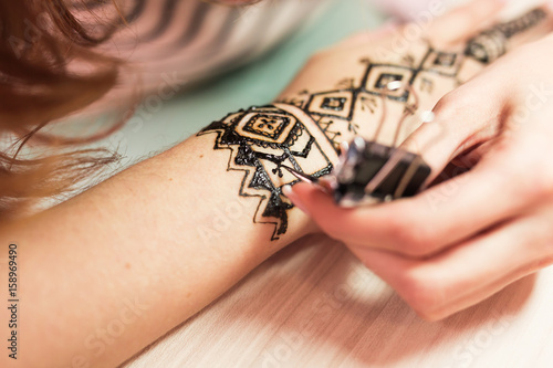 Drawing process of henna menhdi ornament on woman's hand.