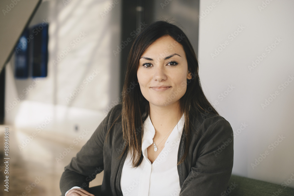 Portrait of confident businesswoman sitting on sofa at office lobby Portrait of confident businesswoman sitting on sofa at office lobby