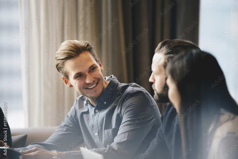 Happy businessman talking to colleagues in brightly lit office Happy businessman talking to colleagues in brightly lit office