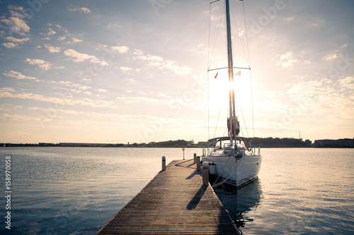 Sailing yacht moored to the pier at sunset