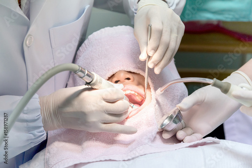 Close up of young Asian Pre teen girl having dental professional treatment in stomatology clinic. Kid at dental office, dentist examining and cleaning her teeth of tartar and plaque.