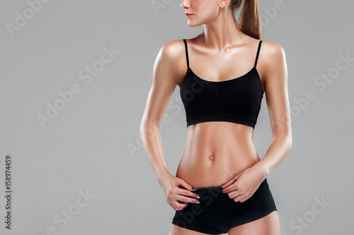 Muscular young woman athlete on gray