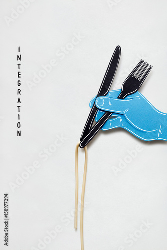 Foto Bon apetit / Creative concept photo of a hand with fork knife and pasta made of paper on white background