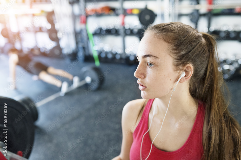 Fototapeta premium Young woman in gym, earphones in her ears,listening music