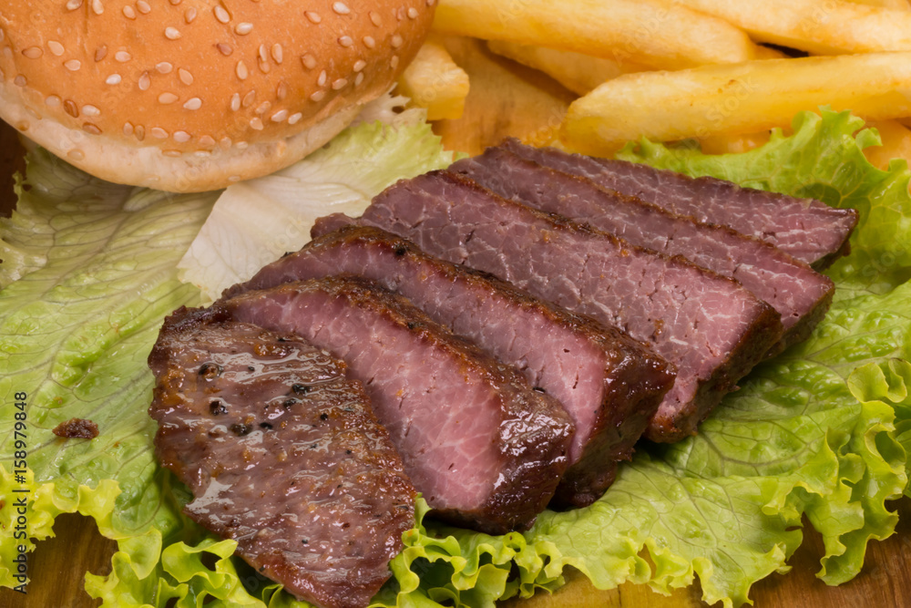 Grilled beef steaks, French fries and vegetables close-up