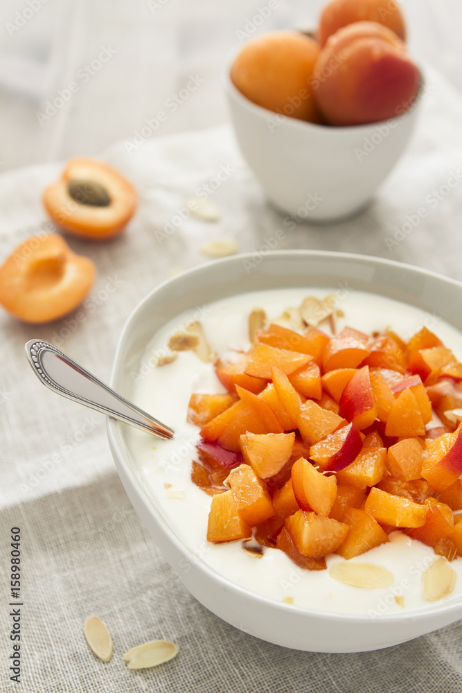 Joghurt mit Aprikosen und Mandelsplitter, mit Löffel auf Leinenserviette Joghurt mit Aprikosen und Mandelsplitter, mit Löffel auf Leinenserviette