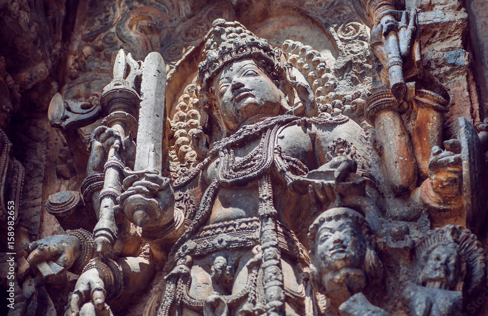 Fototapeta premium Beautiful warrior Shiva Lord on ancient relief of Hindu structure walls with patterns. 12th centur Hoysaleshwara temple in Halebidu, India.