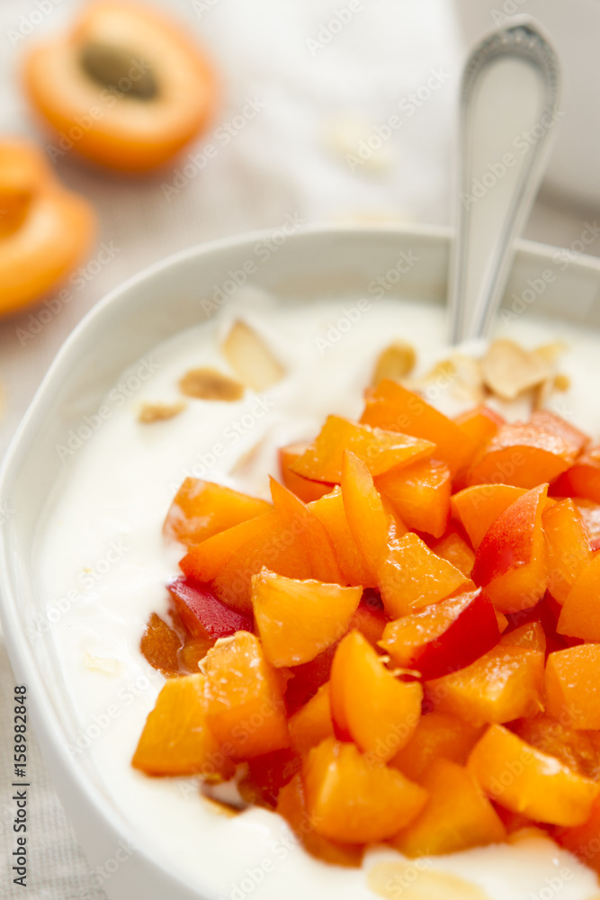 Griechisches Joghurt mit Aprikosen in einer Schüssel auf Leinenserviette Griechisches Joghurt mit Aprikosen in einer Schüssel auf Leinenserviette