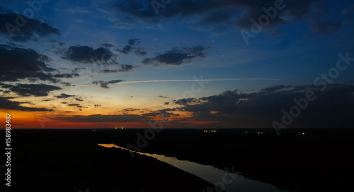 Starry sky with clouds over the river after sunset.