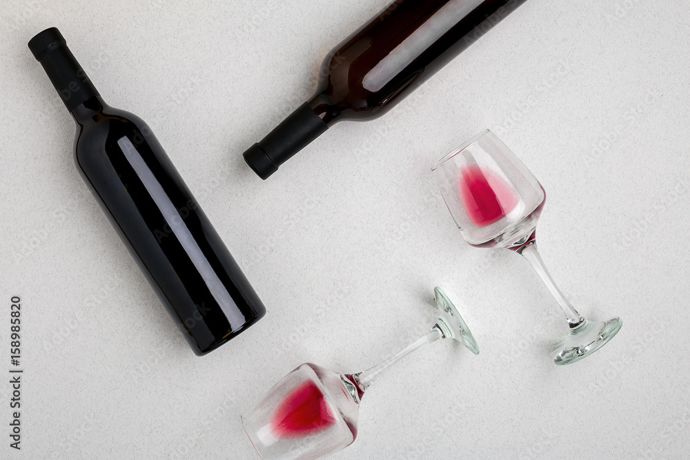 Glasses and bottles of red and white wine on white background from top view Glasses and bottles of red and white wine on white background from top view