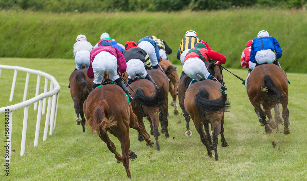 Horse race going around the track kicking up earth and grass Horse race going around the track kicking up earth and grass