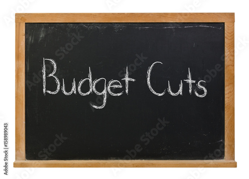Budget Cuts written in white chalk on a black chalkboard isolated on white