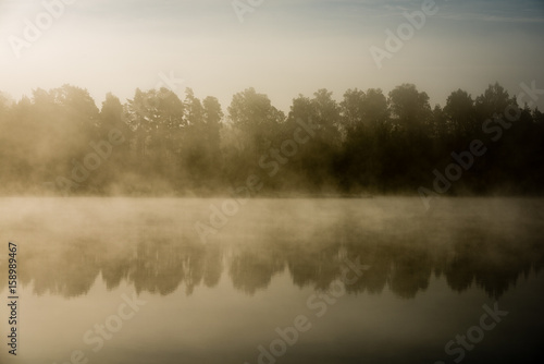 reflections in the lake water in the morning mist