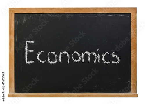 Economics written in white chalk on a black chalkboard isolated on white