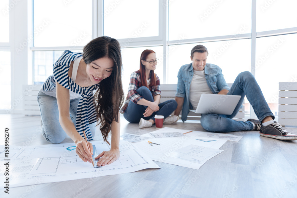 Joyful Asian woman working on a blueprint Joyful Asian woman working on a blueprint