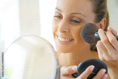 Portrait of beautiful woman putting makeup on