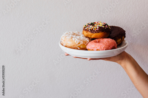 Female hand holding plate of doughnut holes