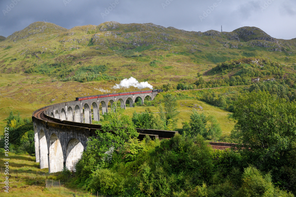 Hogwarts express from Harry Potter. An old train on a mountain valley. Steam comes from the pipe. Scotland