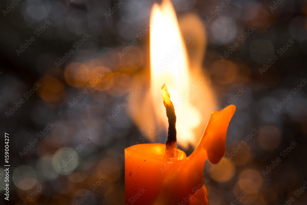 One candle flame light at night with bokeh on dark background One candle flame light at night with bokeh on dark background